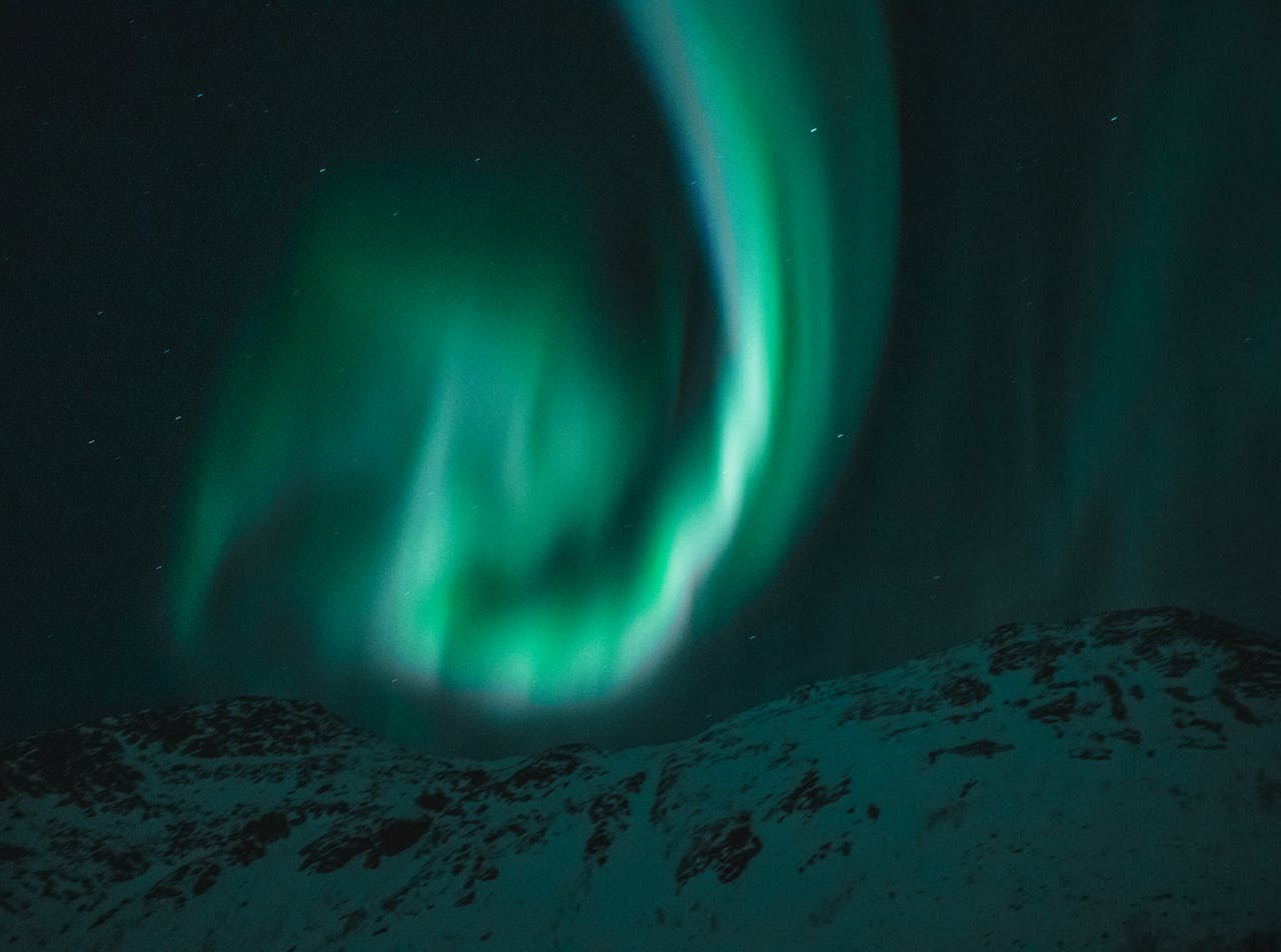 creative-02 Beautiful aurora borealis illuminating the night sky over snow-covered mountains under a starry sky.