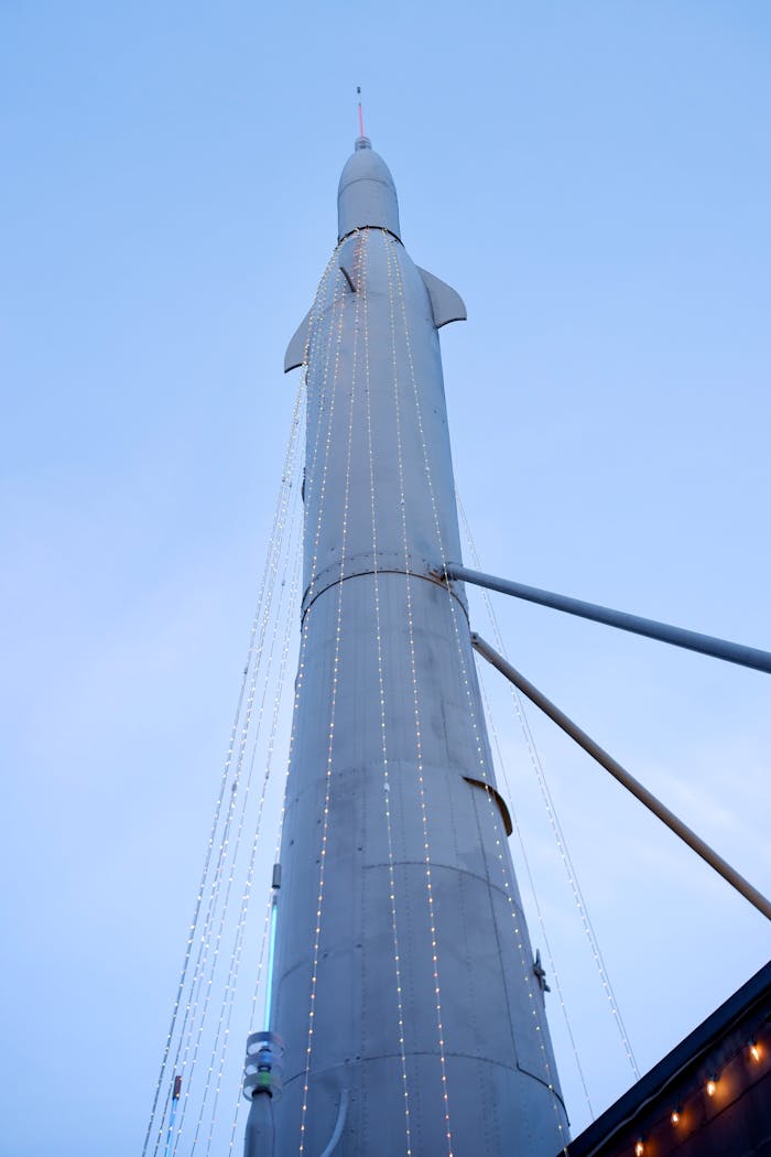 View of a tall rocket with decorative lights set against a clear blue sky.